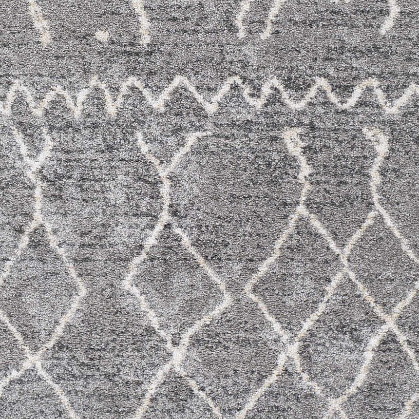 Close-up of the Kessingland Area Rug, showcasing its gray, charcoal, and off-white bohemian diamond pattern and soft texture. Swatch