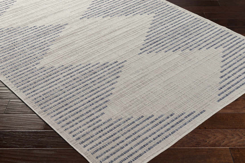 Close-up of the Khandallah Area Rug, a cream rug with a geometric pattern of dark gray and navy stripes. Corner