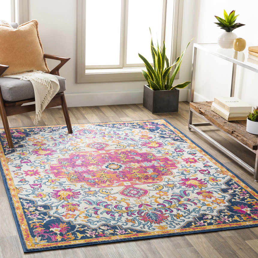 Living room scene with a Kialla Magenta & Burnt Orange Area Rug, chair, side table, plants, and wood floors. Roomscene-Rectangle