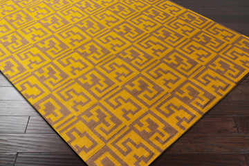 Close-up of the hand woven Kimberton Area Rug. Dark brown and mustard geometric pattern on a 100% wool rug. Corner