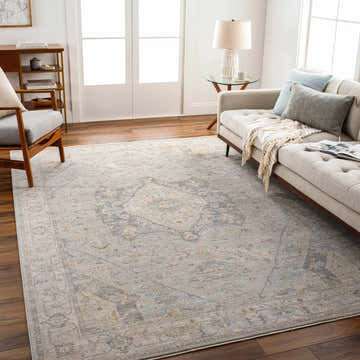 Living room scene with a Kimi Thick Luxe Area Rug in brown, gray, and sage, styled with a sofa, chair, and wood floors. Roomscene-Rectangle