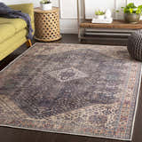 Living room scene with Kittrell Vintage Flat Pile Washable Rug, green sofa, wood side table, and gray pouf. Bohemian style. Roomscene-Rectangle