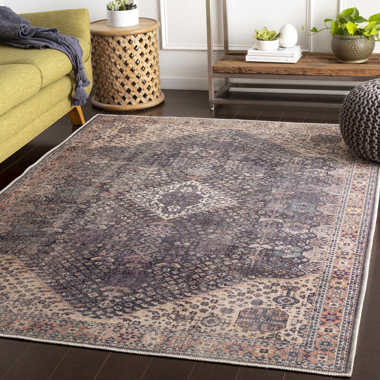 Living room scene with Kittrell Vintage Flat Pile Washable Rug, green sofa, wood side table, and gray pouf. Bohemian style. Roomscene-Rectangle