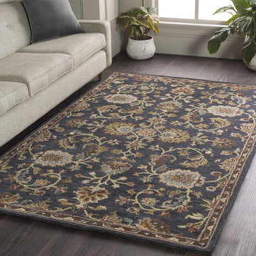 Living room scene with a Kittredge Floral Black Wool Rug, beige sofa, dark wood floors, and potted plants by the window. Roomscene-Rectangle
