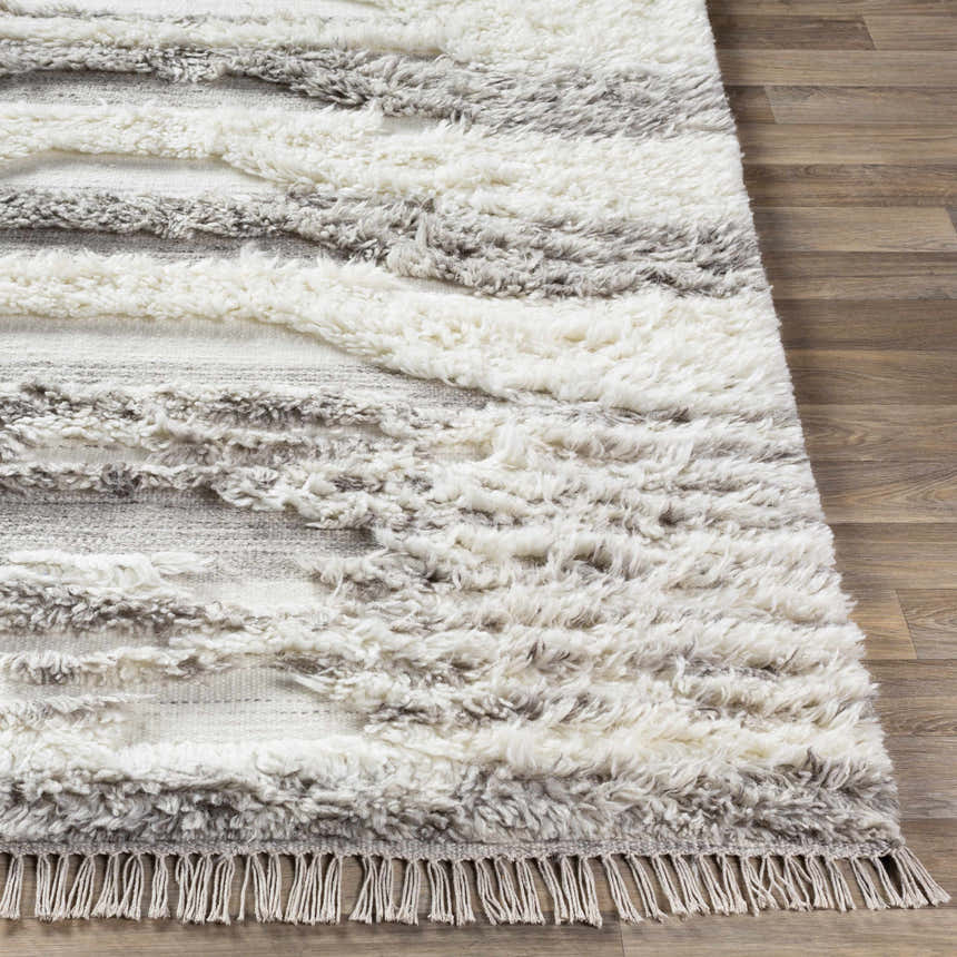 Close up of the hand woven Kingsthorpe Area Rug showing cream, taupe and dark brown shag stripes and fringe detail. Front