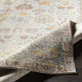 Close-up of the machine-woven Knottsville Area Rug. Features a vintage, traditional design in gray, ivory, yellow, and red tones. Fold