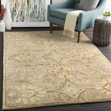 Living room scene with a Chesterton Hand Tufted Ivory rug, blue chair, and modern art. The rug has a floral pattern with ivory and sage tones. Roomscene-Rectangle