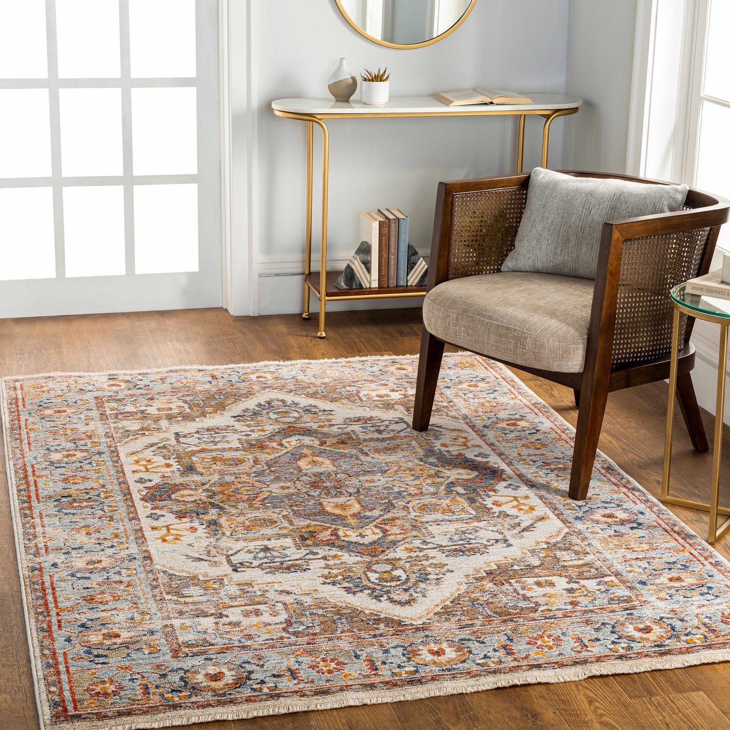 Entryway scene with Kokstad Area Rug in arctic stone, beige, brown. Traditional rug styled with chair, gold table, and wood floors. Roomscene-Rectangle