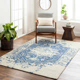 Living room scene with Koppies Area Rug in bone and denim, gray chair, wood accents, and natural light. Roomscene-Rectangle