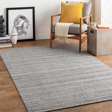 Living room scene with gray Koyulhisar Area Rug, wood chair with yellow pillow, and modern decor. Roomscene-Rectangle