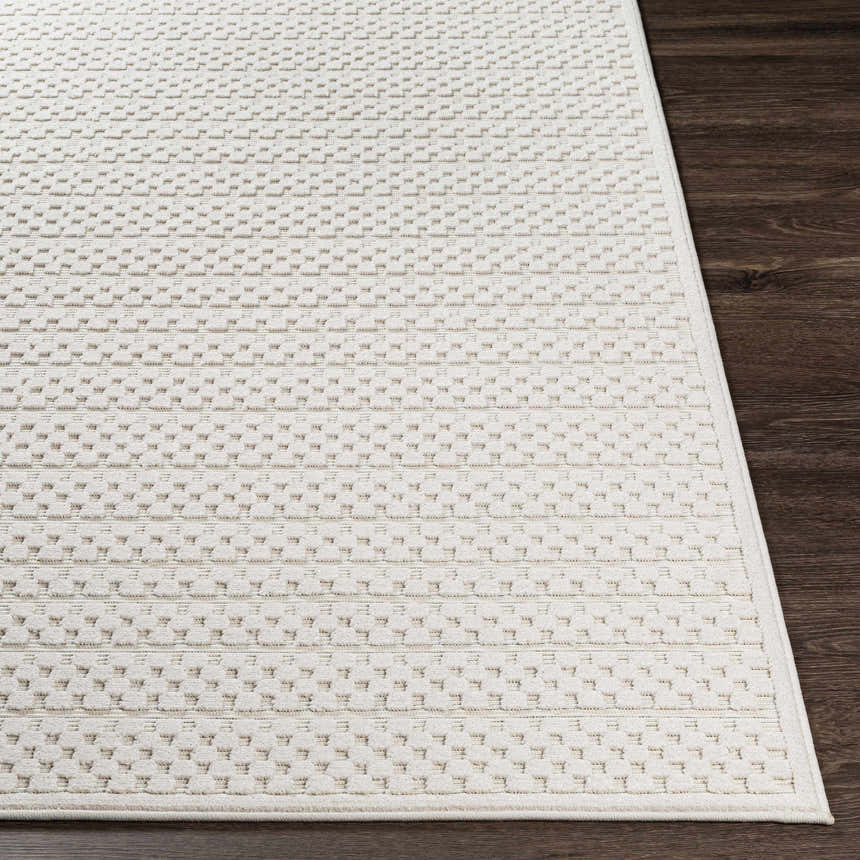 Close-up of the Kirkburton Beige Outdoor Rug showing a textured, geometric pattern in light beige on dark wood flooring. Front