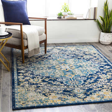 Living room scene with a blue and off-white Kurnell Area Rug, armchair, side table, and plants by the window. Roomscene-Rectangle