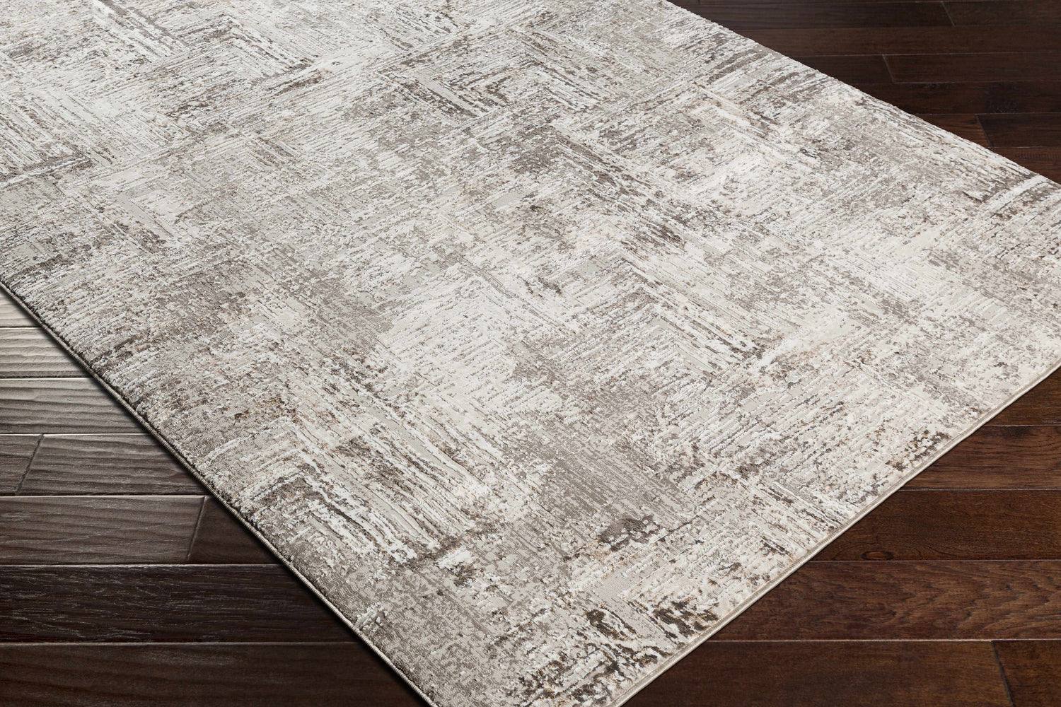 Close-up of the Kutloanong Area Rug showing its charcoal, gray, and ivory contemporary design on dark wood flooring. Corner