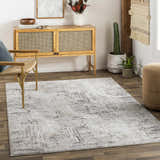 Living room scene with a gray and ivory Kutloanong Area Rug, woven chair, and wooden cabinet. Contemporary style. Roomscene-Rectangle