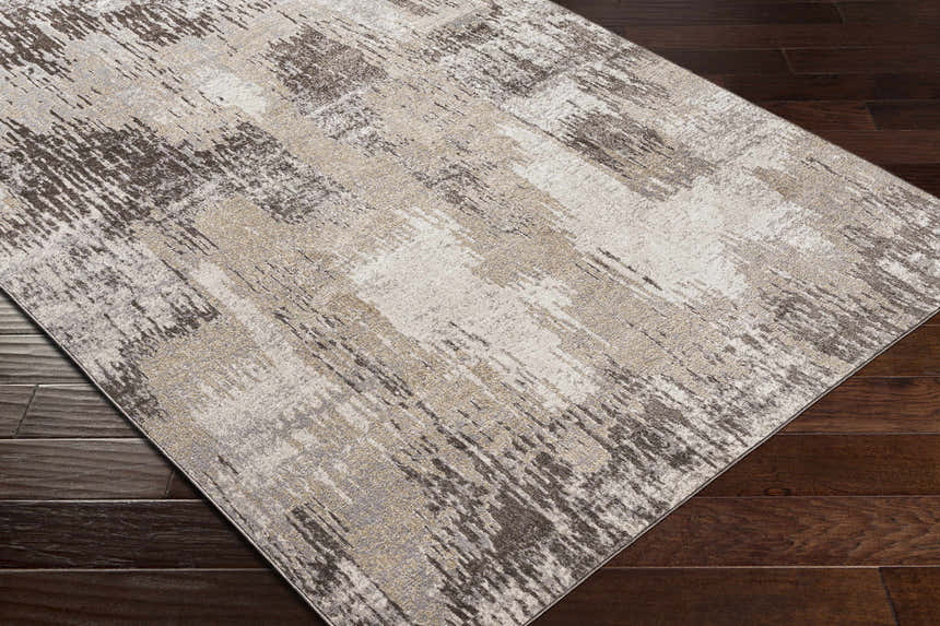 Close-up of Kuyucak Washable Area Rug. Contemporary design in brown, cream, gray, light beige, and taupe on dark wood floor. Corner