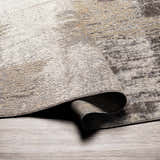 Close-up of the Kuyucak Washable Area Rug showing its brown, cream, and gray abstract design and soft, textured weave. Fold