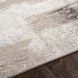 Close-up of the Kuyucak Washable Area Rug. Abstract design in brown, cream, gray, and light beige. Soft, textured polyester. Texture
