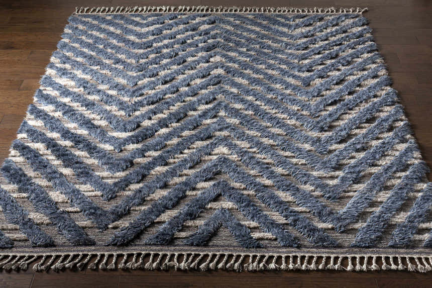 Close-up of the Lambsburg Knotted Wool Rug. Features a blue and beige chevron pattern with a textured, hand-knotted design. Front