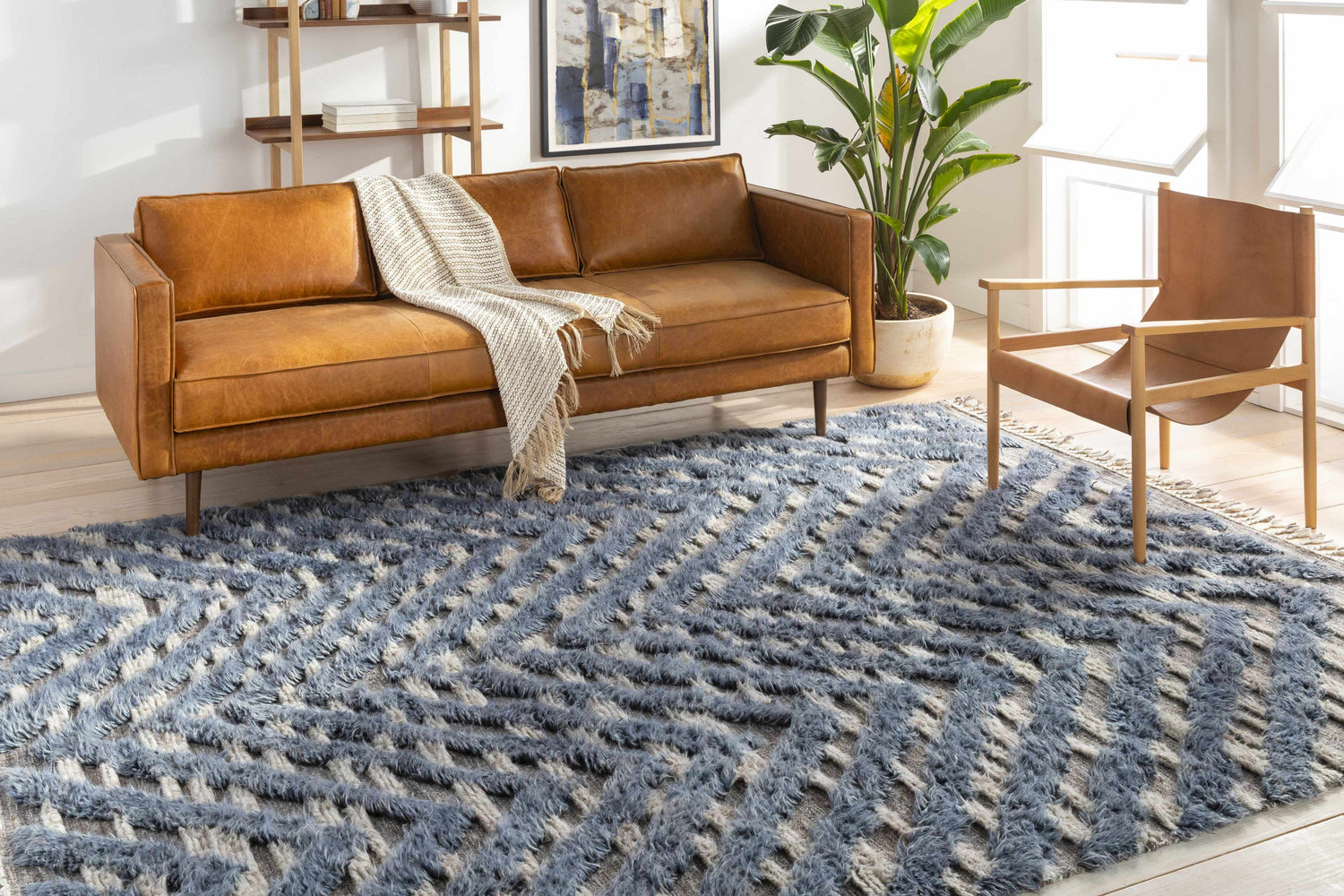 Living room scene with a blue Lambsburg Knotted Wool Rug, leather sofa, and modern chair. Roomscene-Rectangle