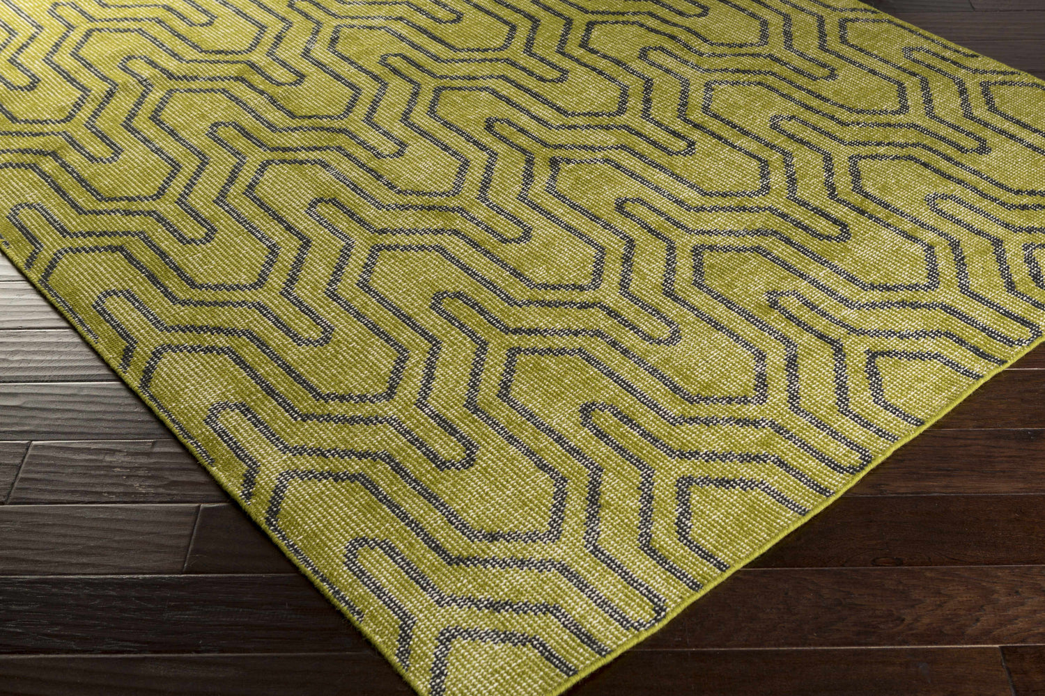 Larchmont Area Rug, green and black geometric pattern, on dark wood floor. Hand-knotted wool rug. Corner