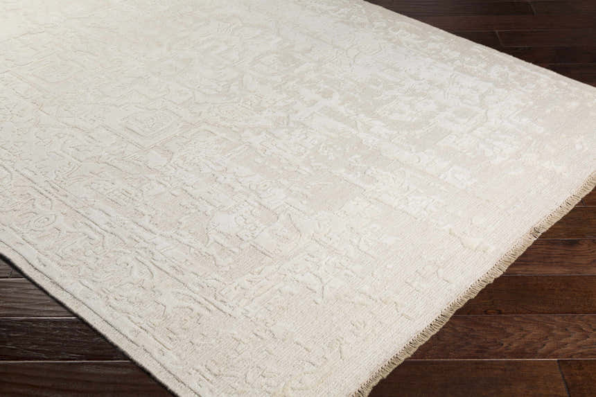 Close up of the ivory Larimer Area Rug showing its hand knotted texture and traditional design on dark wood floors. Corner