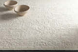 Close-up of the ivory Larimer Area Rug with a raised, textured pattern and two decorative bowls. Styleshot