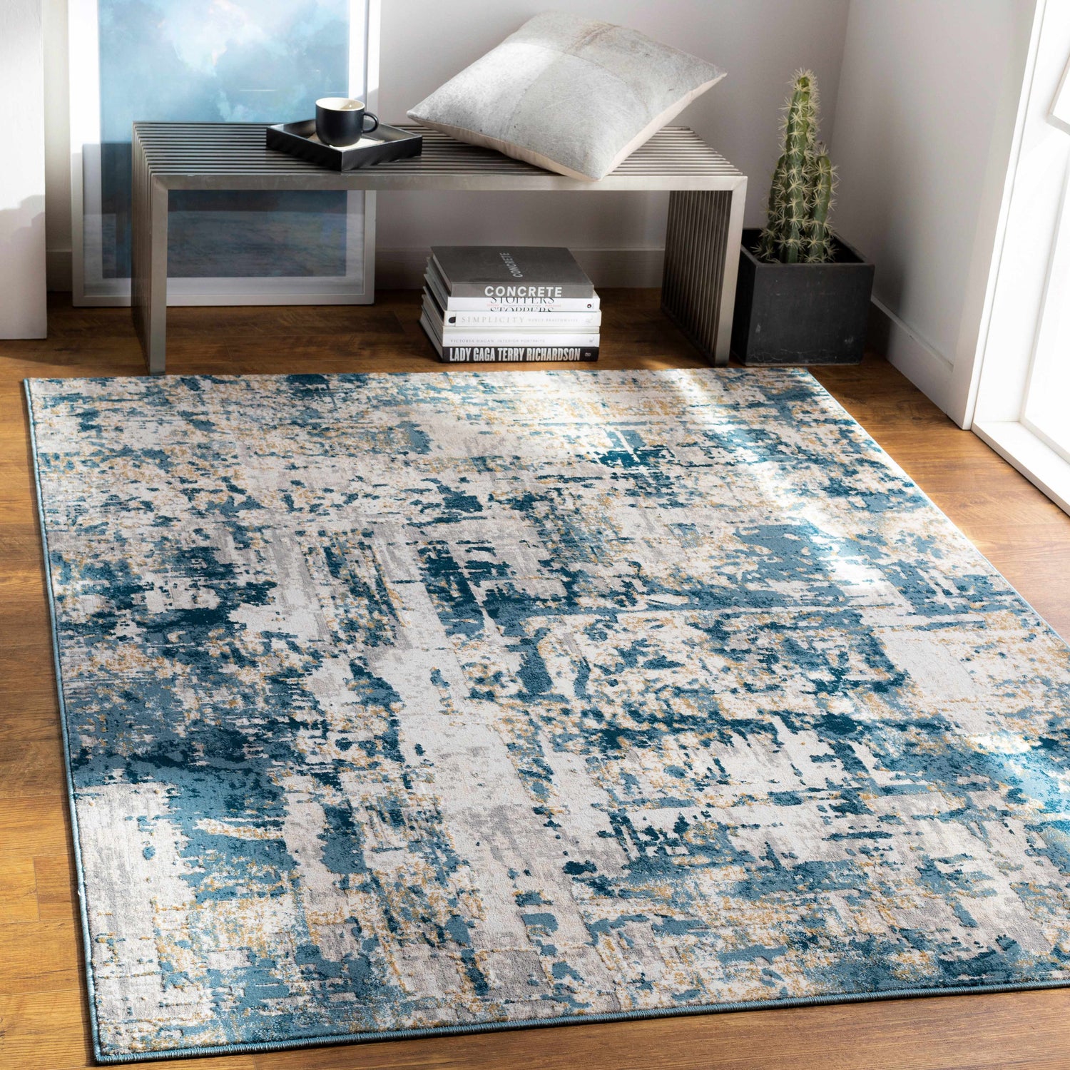 Living room scene with a Larne Area Rug in blue, gray, and beige, styled with a metal bench and wood floors. Roomscene-Rectangle