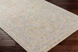 Close-up of the Coby Cream Avant Garde Rug showing its traditional pattern, brown, teal, and gray colors, and luxe texture. Corner