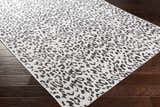 Close up of Alderbury White Leopard Print Rug showing black animal print on off-white polypropylene material. Corner