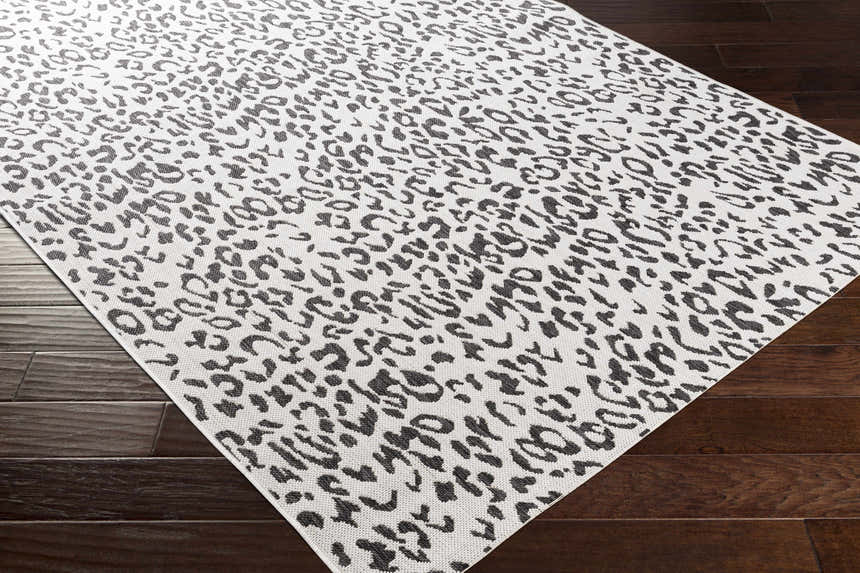 Close up of Alderbury White Leopard Print Rug showing black animal print on off-white polypropylene material. Corner