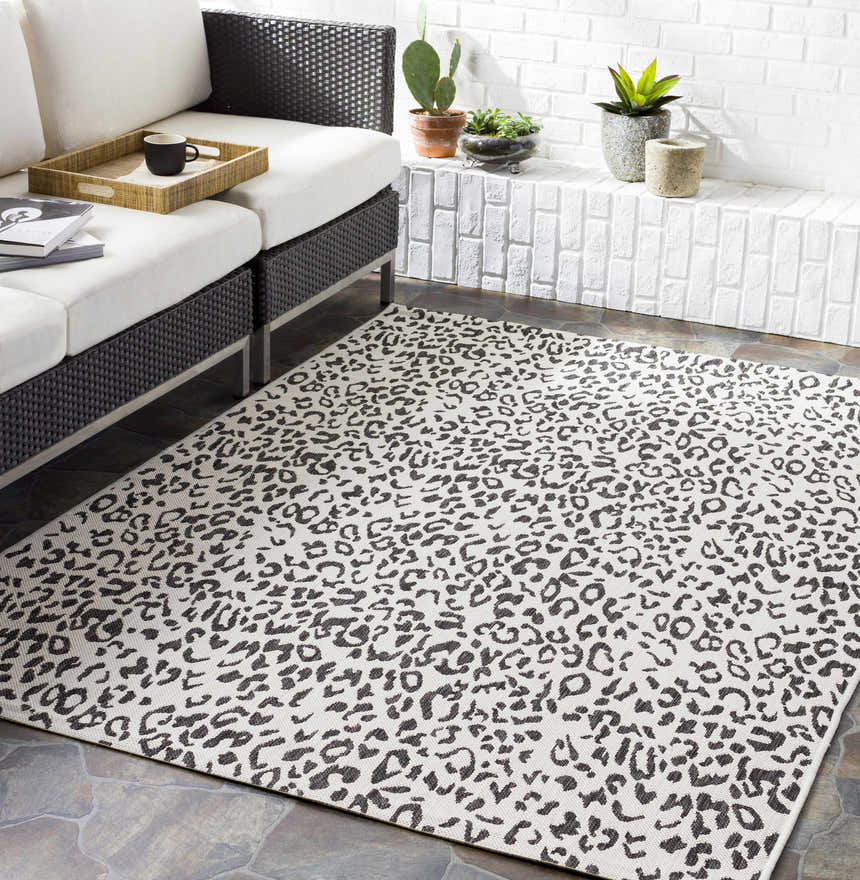 Living room scene with a black and white Alderbury White Leopard Print Rug under a modern black and white sofa. Roomscene-Rectangle