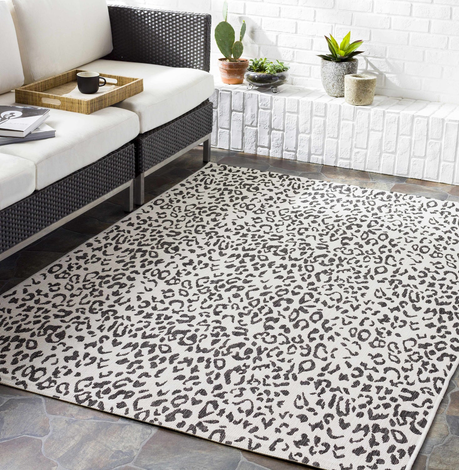 Living room scene with a black and white Alderbury White Leopard Print Rug under a modern black and white sofa. Roomscene-Rectangle