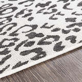Close-up of the Alderbury White Leopard Print Rug showing the black animal pattern on an off-white, textured polypropylene rug. Texture