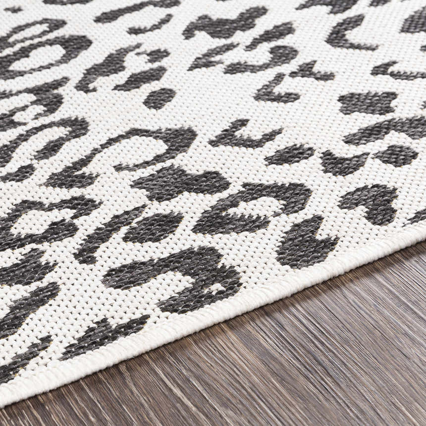 Close-up of the Alderbury White Leopard Print Rug showing the black animal pattern on an off-white, textured polypropylene rug. Texture
