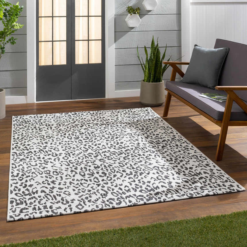 Patio scene with Alderbury White Leopard Print Rug, gray sofa, wood floor, and plants. Roomscene-Rectangle