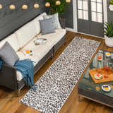 Outdoor patio scene with a white couch and Alderbury White Leopard Print Rug runner on a wood deck. Roomscene-Runner
