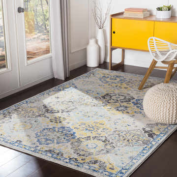 Living room scene with Leggett Hydrangea rug in navy, mustard, and gray. Features a yellow cabinet and white pouf. Roomscene-Rectangle