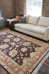 Living room scene with a beige sofa and the brown floral Lenapah Area Rug on hardwood floors in front of a brick wall. Roomscene-Rectangle