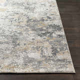 Close-up of Lenzburg Faux Silk Abstract Rug. Charcoal, gray, light gray, and mustard abstract pattern on dark wood floor. Front