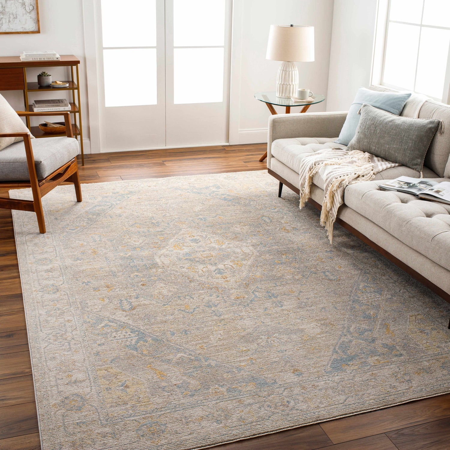 Living room scene with a Leya Thick Luxe Area Rug in charcoal, tan, and blue. Sofa, chair, and wood floors create a cozy feel. Roomscene-Rectangle