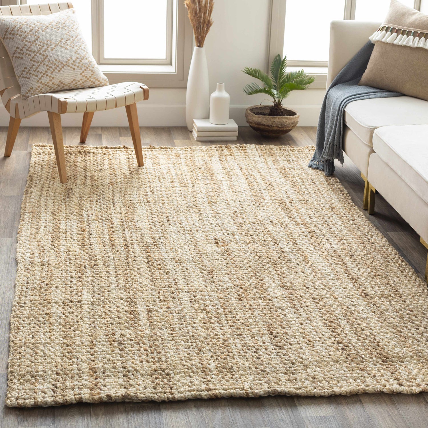 Living room scene with a Leyton Natural Jute Rug, ivory sofa, and woven chair creating a warm, inviting, neutral space. Roomscene-Rectangle