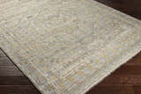 Close-up of the hand-knotted Ligao Area Rug. Charcoal, light gray, tan, and wheat colors with a traditional geometric pattern. Corner
