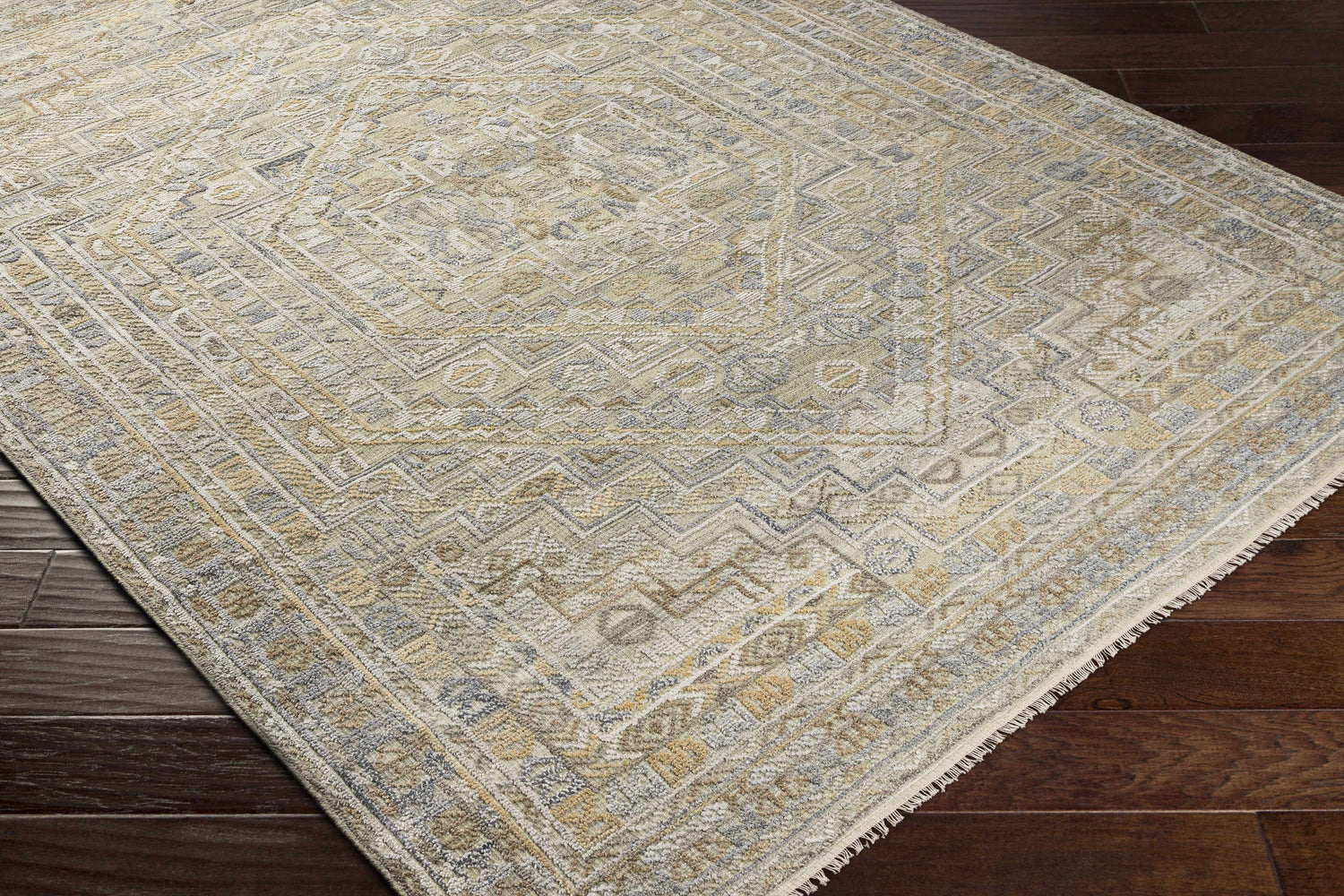 Close-up of the hand-knotted Ligao Area Rug. Charcoal, light gray, tan, and wheat colors with a traditional geometric pattern. Corner