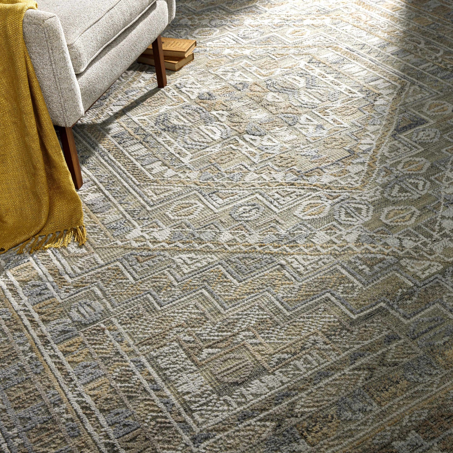 Living room scene with a Ligao Area Rug in charcoal, light gray, tan, and wheat colors under a chair with a yellow throw. Styleshot