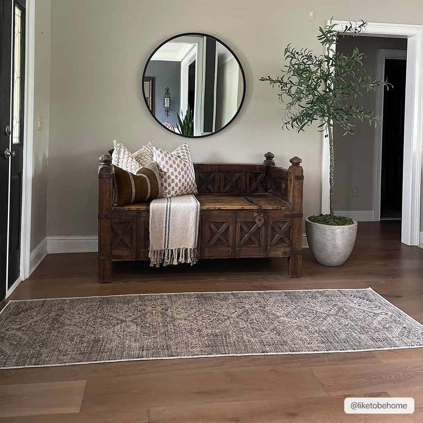 Entryway scene with Barny Beige Flat Pile Washable Rug, wood bench, round mirror, and potted olive tree. Farmhouse style. Roomscene-Runner
