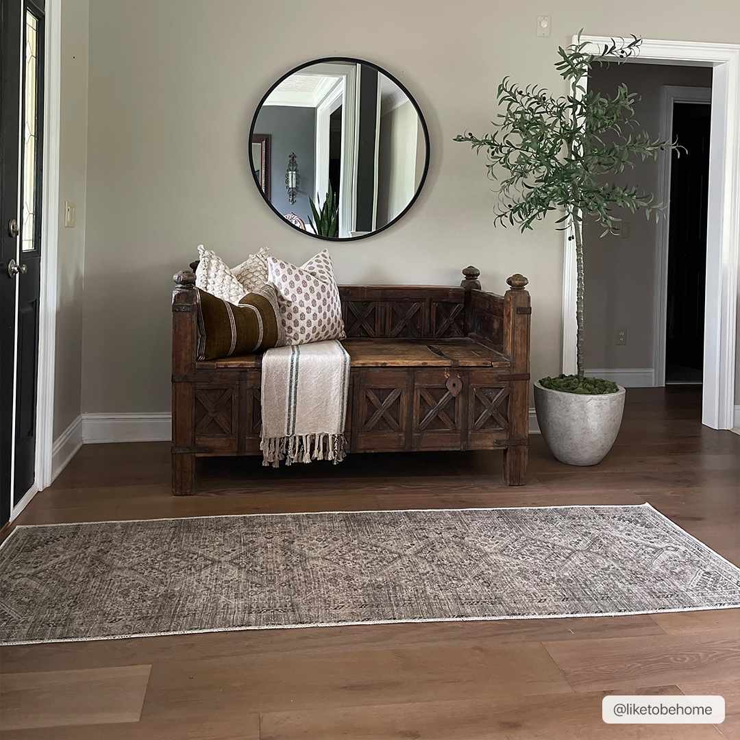 Entryway scene with Barny Beige Flat Pile Washable Rug, wood bench, round mirror, and potted olive tree. Farmhouse style. Roomscene-Runner