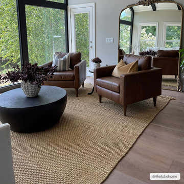 Living room scene with brown leather chairs on a Hovland Hand Woven Natural Jute Rag Rug. Large windows and modern decor. Roomscene-Rectangle