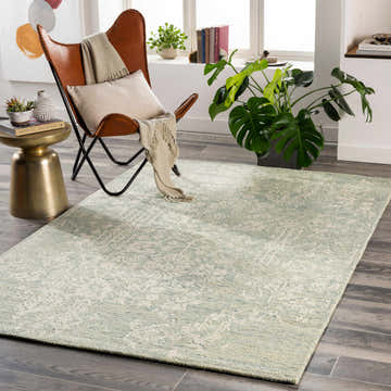 Living room scene with a Linabuan Modern Wool Rug in cream, light green, and teal, leather chair, and plants. Roomscene-Rectangle