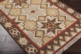 Close-up of the hand woven Liscomb Area Rug. Brown, ivory, mustard, and pale blue geometric pattern. Wool texture. Corner