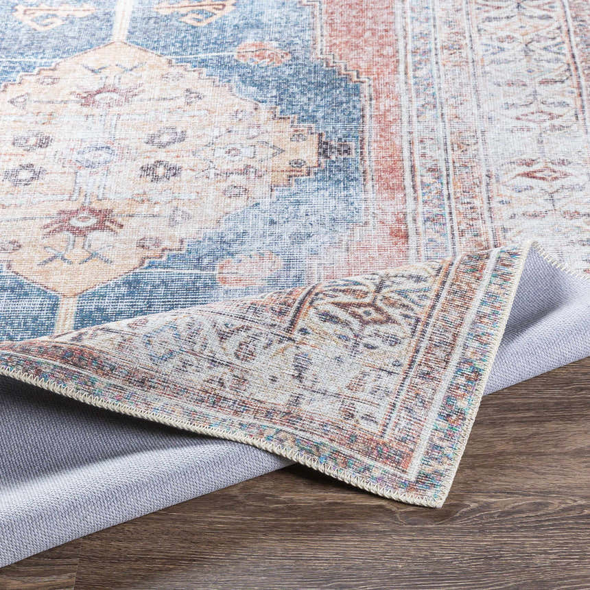 Close-up of the Lake Area Rug, showcasing its bohemian pattern, blue, coral, tan, and gray colors, and machine-woven texture. Fold
